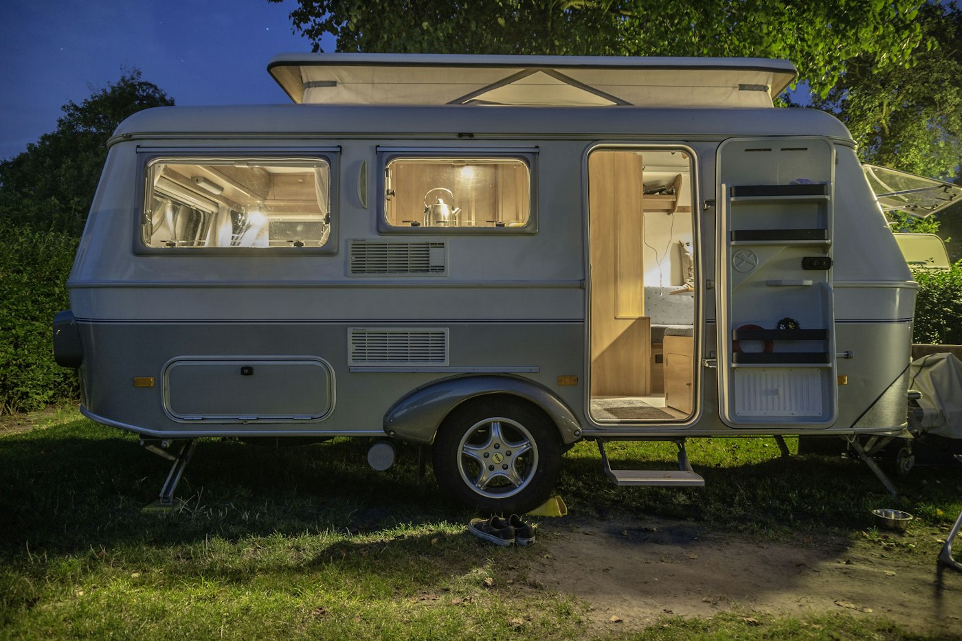 Camper trailer parked beside a tree