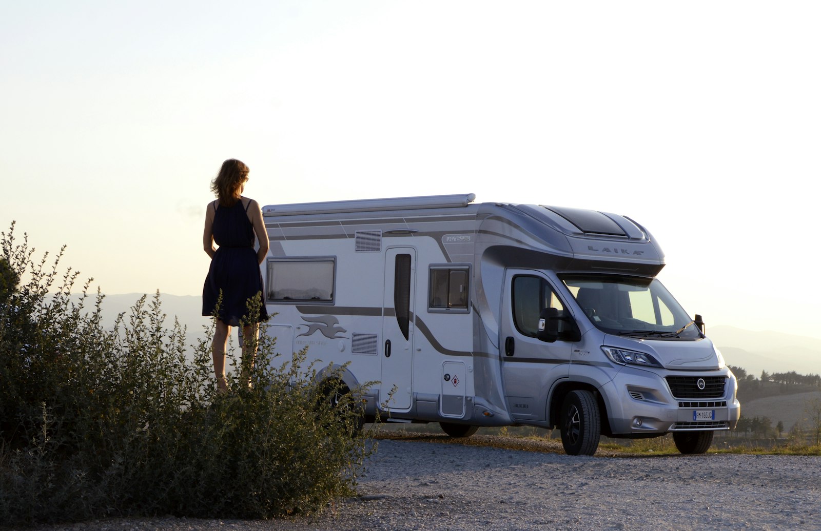 RV owner standing beside a clean white and blue travel trailer after an exterior wash