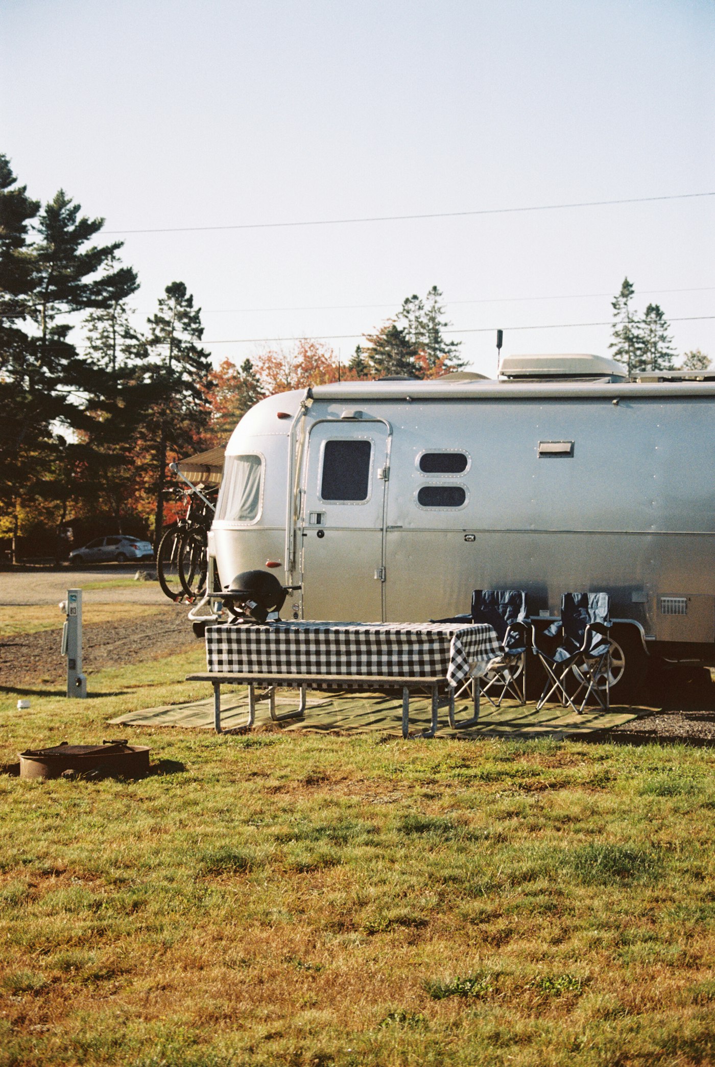 Travel trailer parked at a campsite beside a picnic table